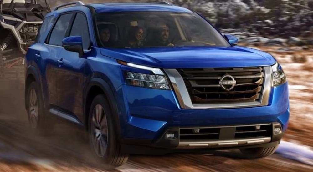 A blue 2022 Nissan Pathfinder is driving on a muddy path.