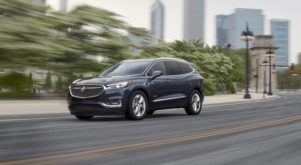 A gray 2021 Buick Enclave is driving on a city highway after leaving a Buick GMC Dealership near you.