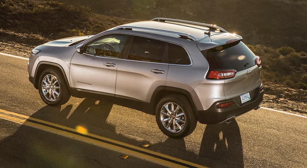 A silver 2018 Certified Pre-Owned Jeep Cherokee is shown from a high angle on a sunny road.