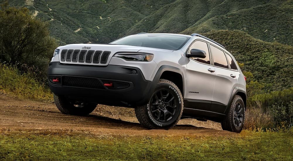 A silver 2019 Certified Pre-Owned Jeep Cherokee is off-roading on a mountain path.