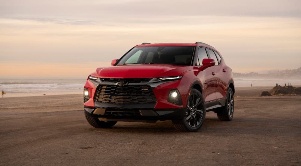 A red 2021 Chevy Blazer is parked on a beach at sunset after leaving a Chevy dealer.