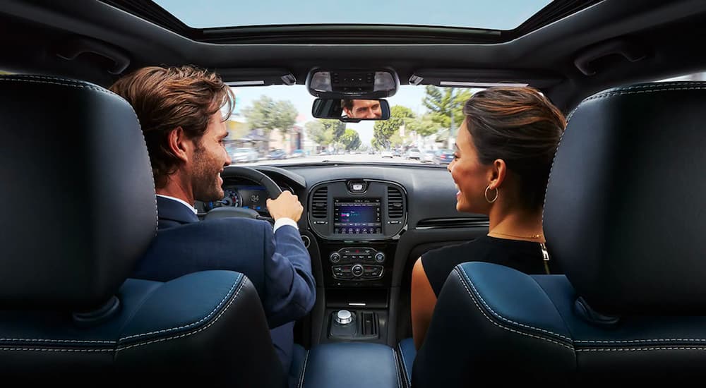 A couple is shown facing each other and talking in the front seats of a 2021 Chrysler 300.