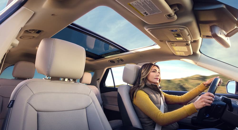 A woman is shown from the passenger side while driving a 2021 Ford Explorer.