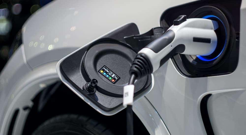 A charging cable is shown plugged into a white EV.
