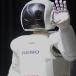 A close up shows ASMIO the robot waving.