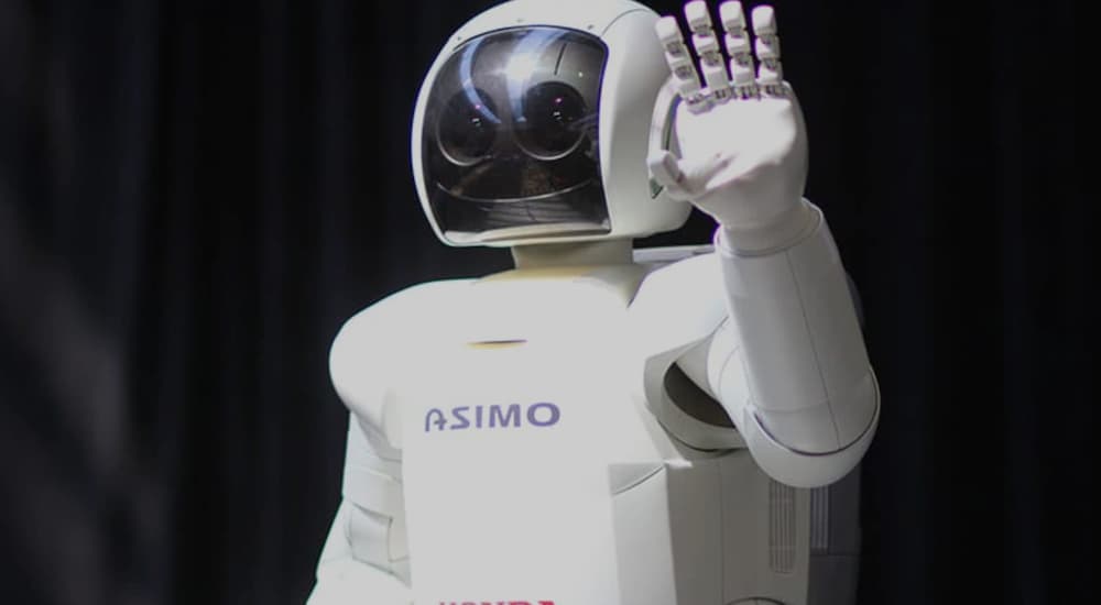 A close up shows ASMIO the robot waving.