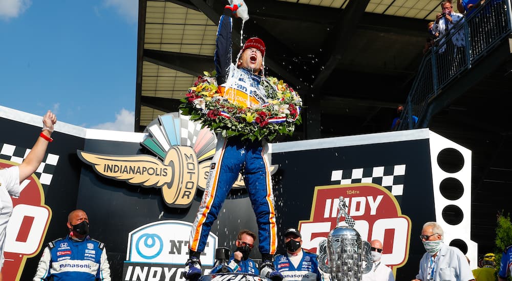 A close up shows Takuma Sato celebrating after winning the Indy 500.