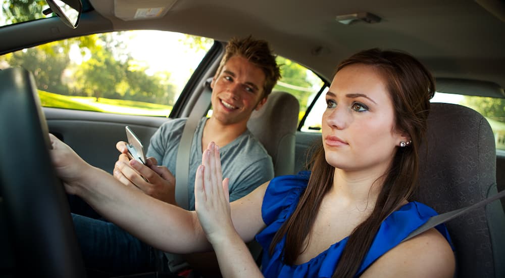 A teen driver is shown ignoring her friend to focus on the road.
