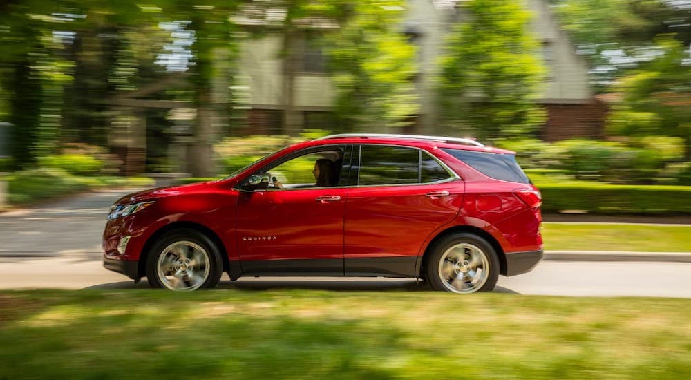 A red 2018 Chevy Equinox is shown from the side driving on a suburban street.