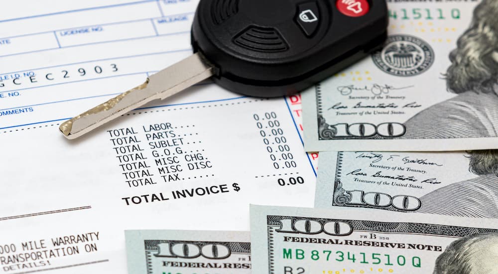 A close up shows service paperwork, car keys, and money.