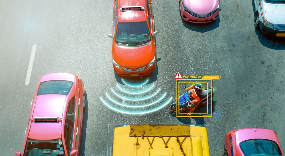 A car with simulated warning sensor lines detecting a motorcycle are shown from a high angle.