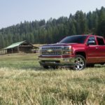 A red 2016 Chevy Silverado LTZ is parked in front of a cabin after leaving a used car lot.