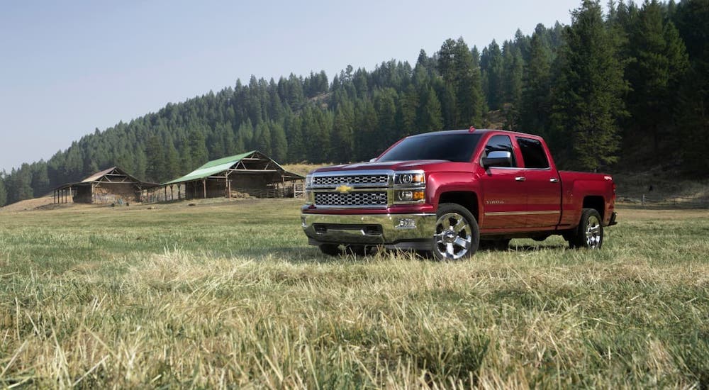 A red 2016 Chevy Silverado LTZ is parked in front of a cabin after leaving a used car lot.