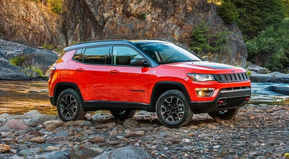 A red 2019 Used Jeep Compass is shown from the side parked next to a river.