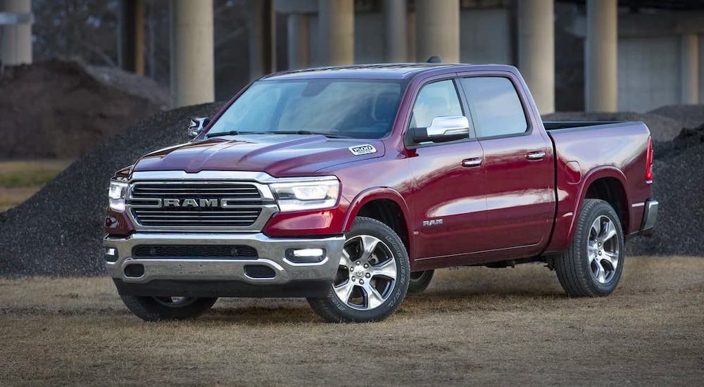 A red 2019 used Ram Laramie is parked in front of gravel piles and pillars.