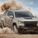 A light brown 2021 Chevy Colorado ZR2 is show at an angle as it drives through sand.