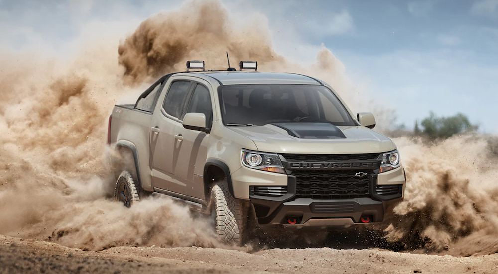 A light brown 2021 Chevy Colorado ZR2 is show at an angle as it drives through sand.