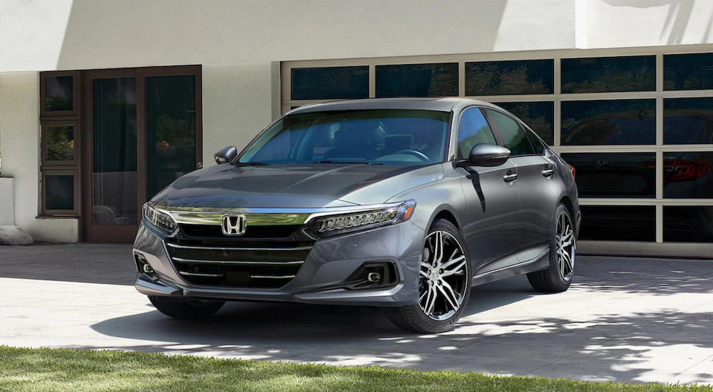 A silver 2021 Honda Accord is parked in front of a modern garage.