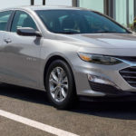 A 2021 Silver Chevy Malibu is parked in a spot next to the beach after winning a 2021 Chevy Malibu vs 2021 Honda Accord comparison.