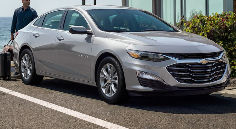 A 2021 Silver Chevy Malibu is parked in a spot next to the beach after winning a 2021 Chevy Malibu vs 2021 Honda Accord comparison.