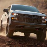 A white 2021 Chevy Silverado 1500 is shown from the front driving off road in the desert.