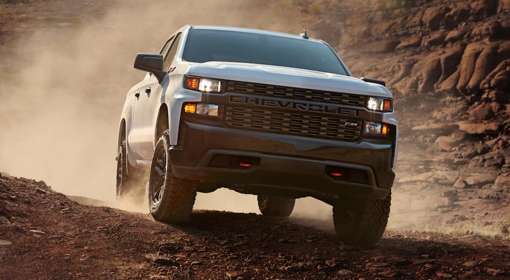 A white 2021 Chevy Silverado 1500 is shown from the front driving off road in the desert.