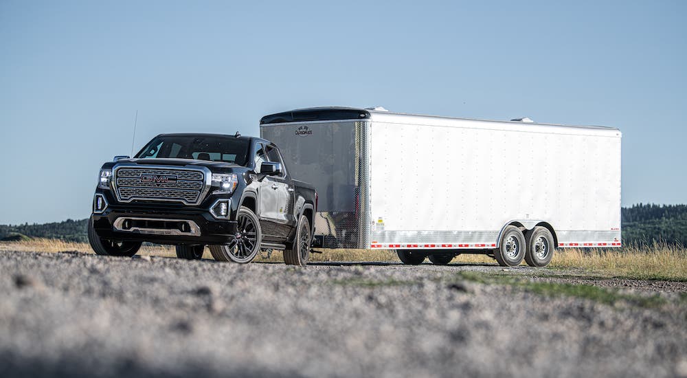 A black 2021 GMC Sierra Denali is towing a large enclosed trailer as part of the 2021 GMC Sierra 1500 vs 2021 Ram 1500 comparison.