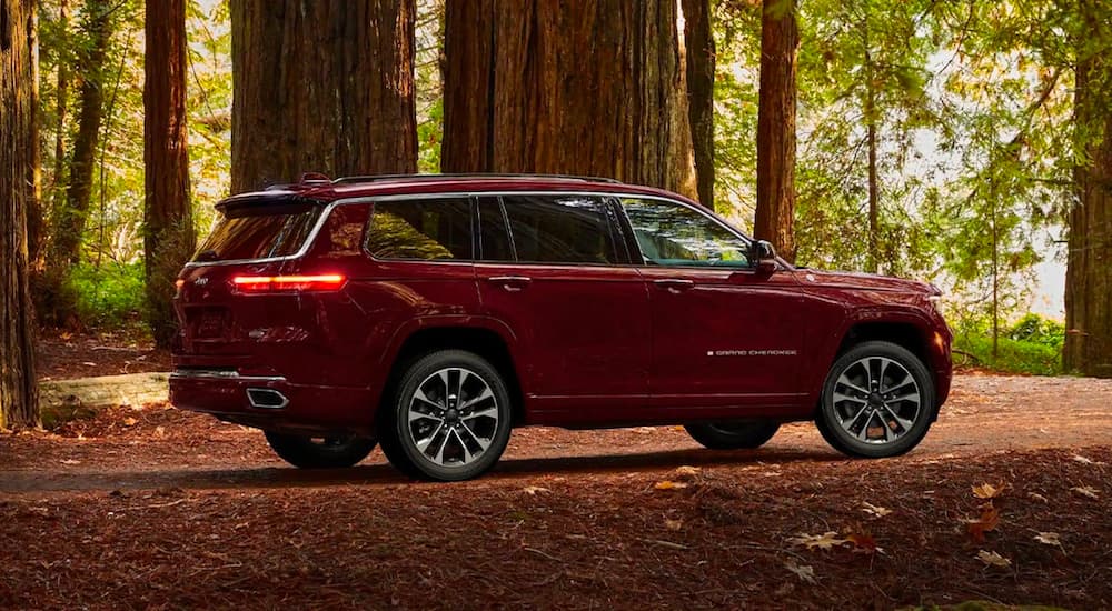 A red 2021 Jeep Grand Cherokee L is shown from the side parked in the woods.