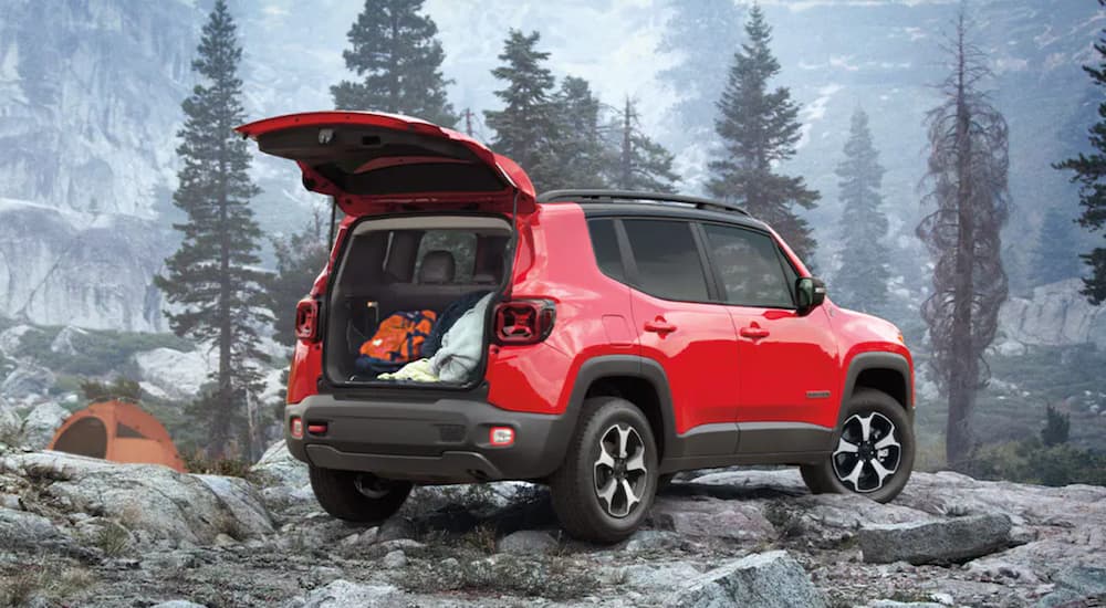 A red 2021 Jeep Renegade is parked in the mountains with the lift gate open.