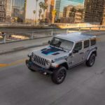 A silver 2021 Jeep Wrangler 4xe is shown from a high angle driving on a city street.
