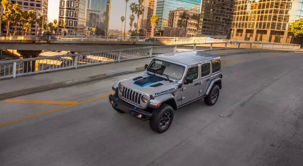 A silver 2021 Jeep Wrangler 4xe is shown from a high angle driving on a city street.