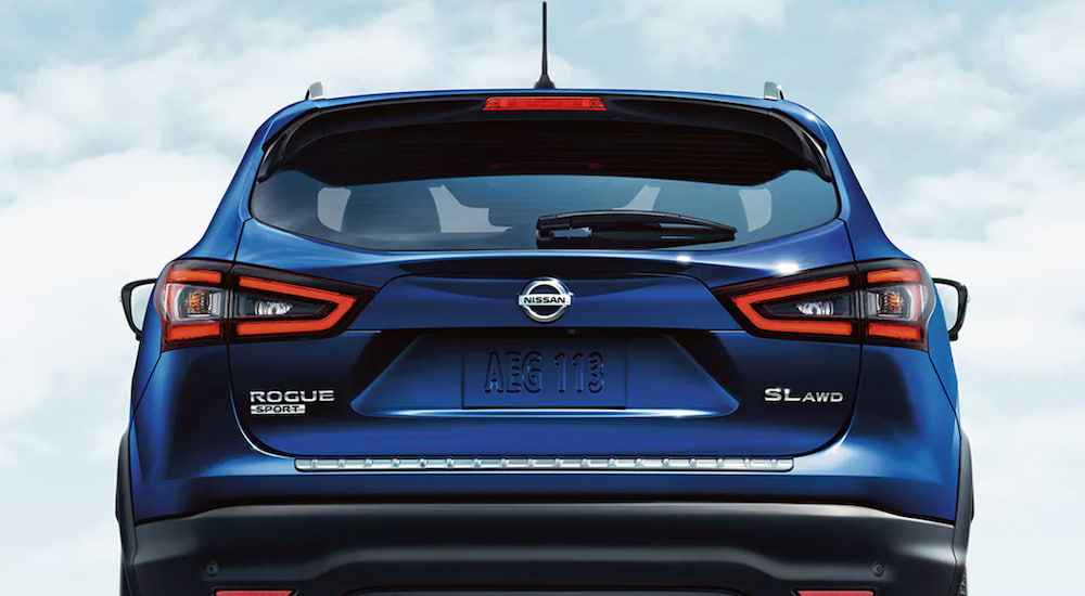 The rear of a blue 2021 Nissan Rogue Sport is shown under a blue sky.