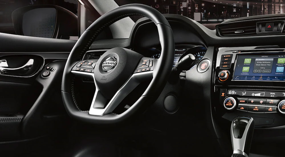 The interior of a 2021 Nissan Rogue Sport shows the steering wheel and infotainment screen.