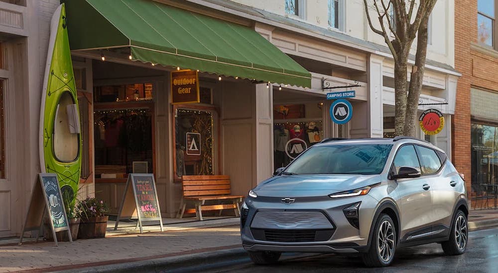 A silver 2022 Chevy Bolt EUV is parked in front of an outdoor gear store.