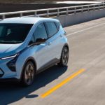A silver 2022 Chevy Bolt EUV is following a pale blue Bolt EV on a highway.