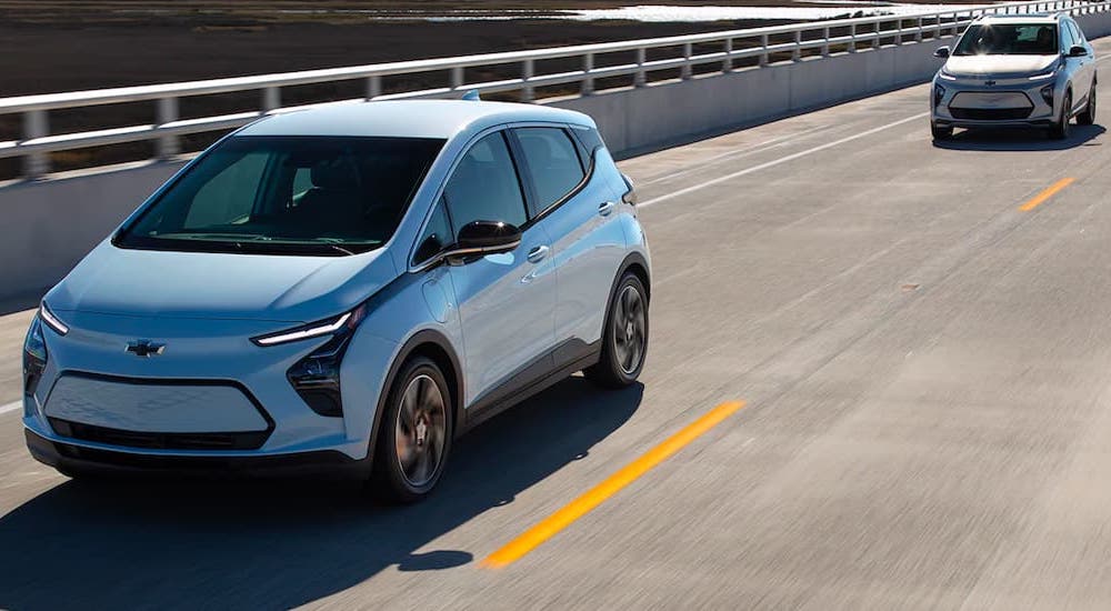 A silver 2022 Chevy Bolt EUV is driving behind a bolt EV on the road.