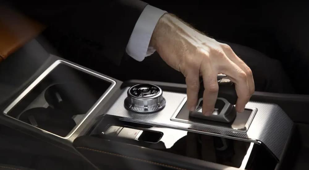 A man in a suit has his hand on the shift lever of a 2022 Mitsubishi Outlander.