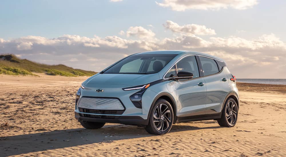 A light blue 2022 Chevy Bolt EV is parked on the beach after leaving the Chevy EV Dealer.