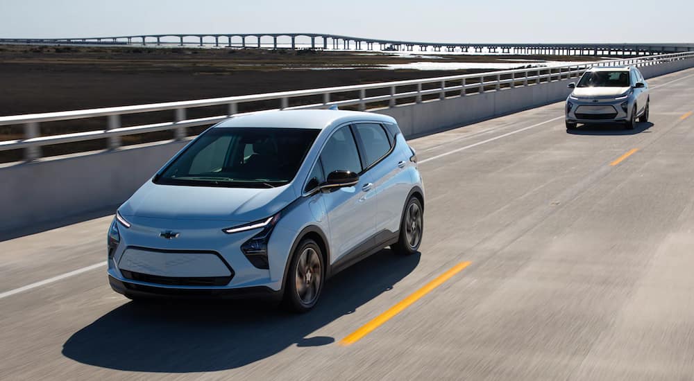 A light blue 2022 Chevy Bolt EV is driving on a bridge before its Chevy end of lease.