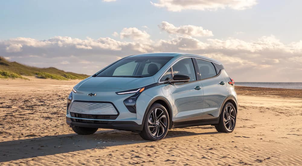 A light blue 2022 Chevy Bolt EV is parked on a beach. 