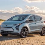 A light blue 2022 Chevy Bolt EV is parked on the beach after leaving an electric car dealership.