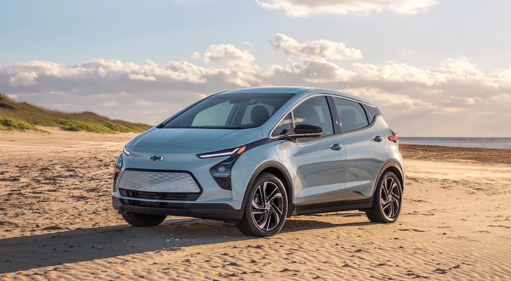 A light blue 2022 Chevy Bolt EV is parked on the beach after leaving an electric car dealership.