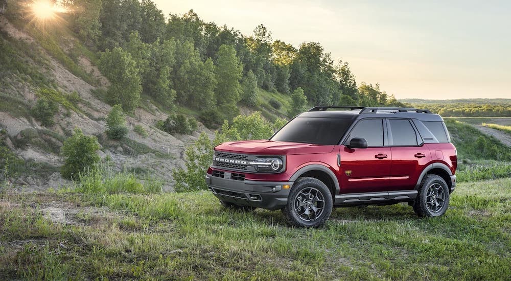 A red 2021 Ford Bronco Sport from a local Ford Bronco Sport dealer is parked in front of a hill covered in trees.