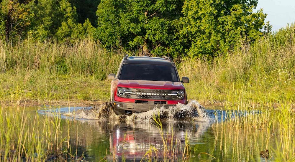 A red 2021 Ford Bronco Sport is shown from the front driving through a pond.