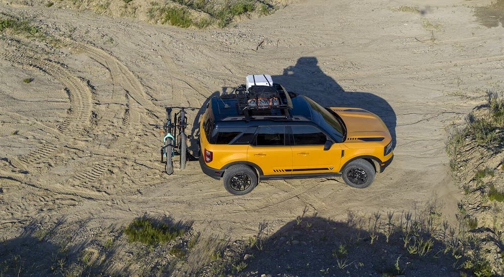 A yellow 2021 Ford Bronco Sport is shown from a high angle while driving on a dirt trail.