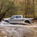 A silver 2021 Ford F-150 Tremor is shown from the side splashing through a river after leaving a Ford dealer..