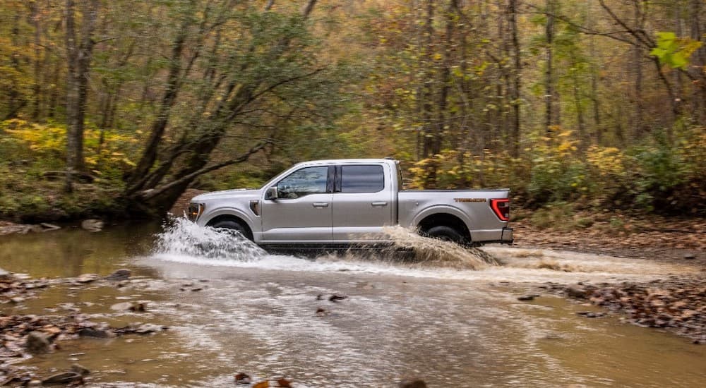 A silver 2021 Ford F-150 Tremor is shown from the side splashing through a river after leaving a Ford dealer..