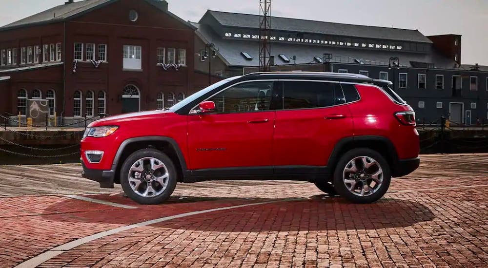 A bright red 2021 Jeep Compass is shown from the side while parked on a pier.