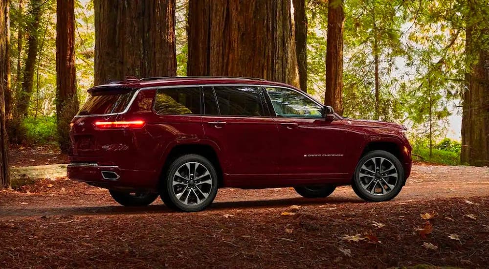 A dark red 2021 Jeep Grand Cherokee L is parked in the woods.