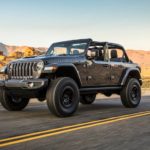 A gray 2021 Jeep Wrangler Unlimited Rubicon 392 with no roof is driving on a desert highway.